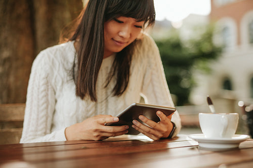 Chinese woman using digital tablet at outdoor cafe