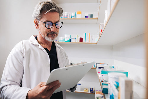 Pharmacist writing on a clipboard in a chemist