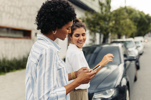 Happy young women e-hailing a taxi in the city