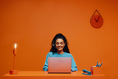 Monochromatic front shot of a woman working on a laptop with colorblocking elements.
