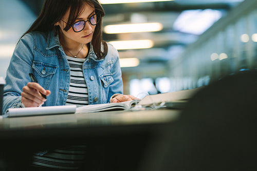 Female student reading a book and writing notes