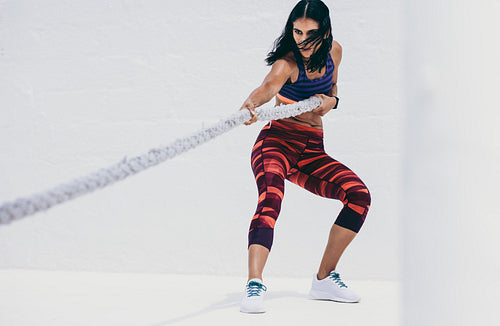 Fitness woman doing strength training using a battle rope