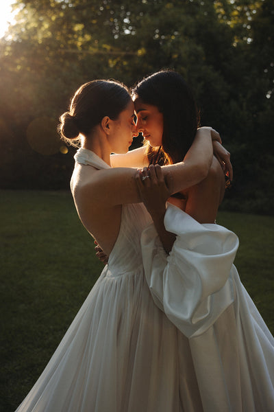 Romantic couple embracing outdoors in elegant wedding attire during sunset