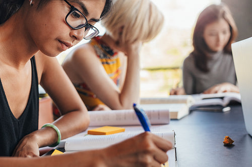 Students sitting at library with books and studying