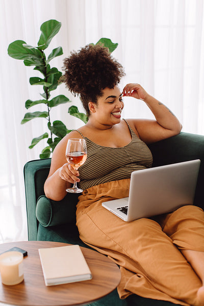 Pretty woman sitting on sofa video calling on laptop