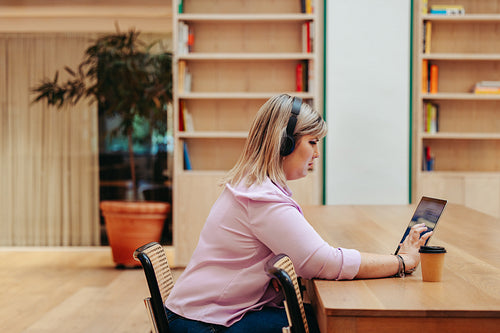 Caucasian businesswoman wearing headphones working on a tablet