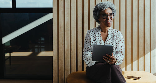 Professional mature businesswoman using a tablet in modern office setting