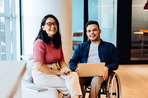 Friends in office collaborate with devices and smiles