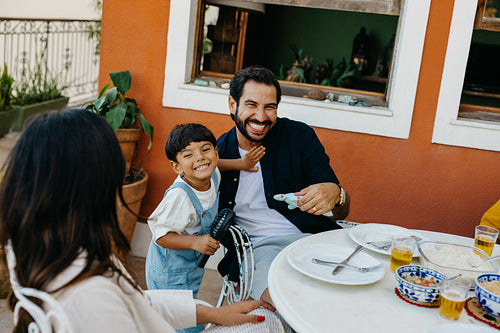 Father and son smiling while enjoying a family meal outdoors