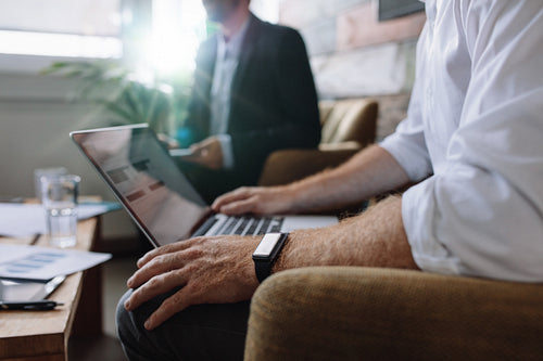 Businessman working on laptop during corporate meeting