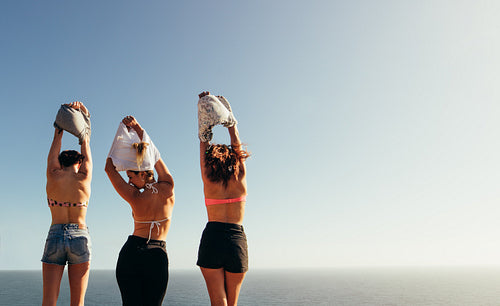 Women removing their tops against seascape