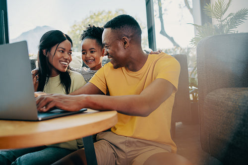 Black family using a laptop together in the living room