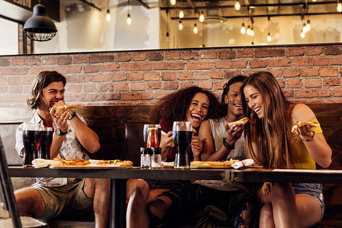 Group of friends having pizza at restaurant