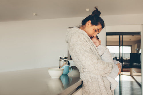 Woman in bathrobe with her son in kitchen 