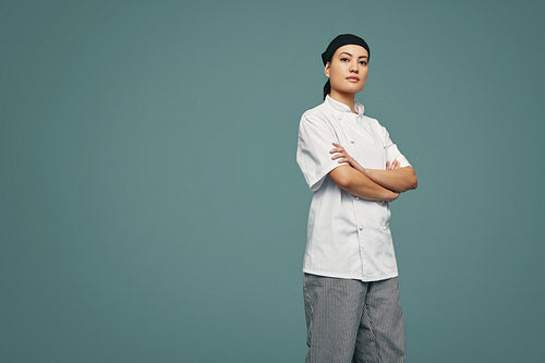 Young culinary chef standing with her arms crossed in a studio