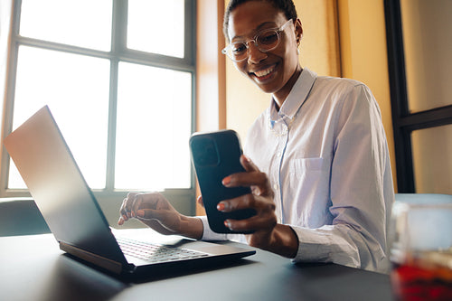 Professional businesswoman using a laptop and phone in a stylish office