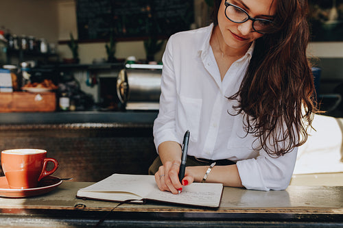 Woman in the cafe writing notes in a book