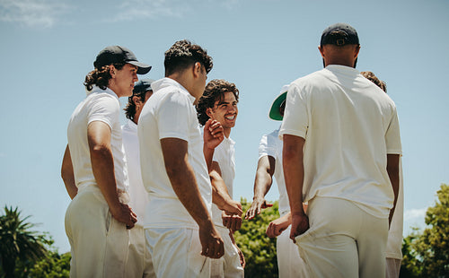 Group of male cricket players strategizing together under the sunny sky