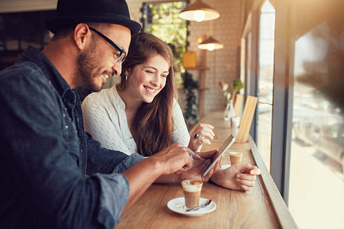 Happy couple in a coffee shop using digital tablet