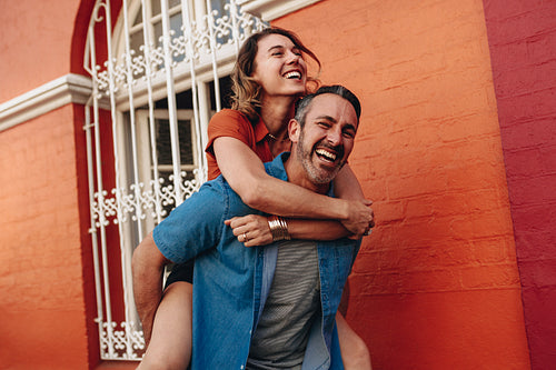 Couple piggybacking on city street