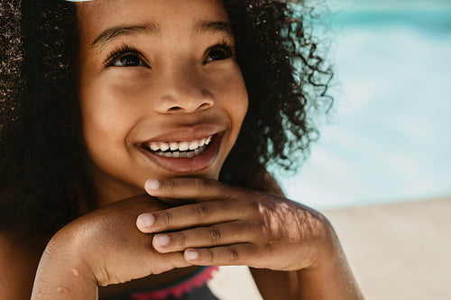 Cute girl sitting by a swimming pool