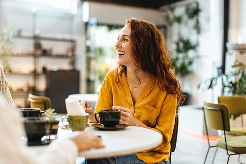 Happy woman enjoying coffee with friends in a restaurant