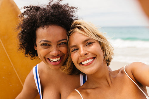 Happy female surfers capturing fun beach moments with a selfie