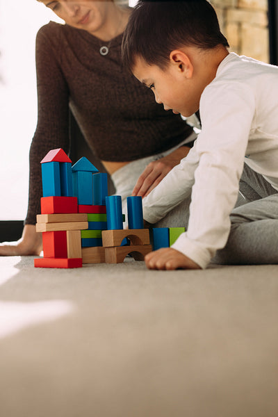 Child playing colorful blocks game with mother