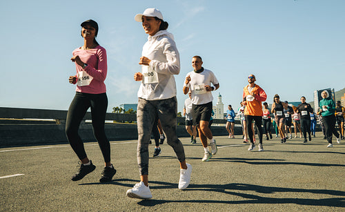 Pair of female runners leading a marathon race on sunny day
