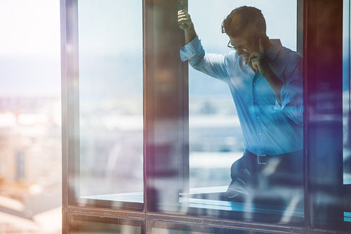 Smiling businessman inside office and talking on cell phone