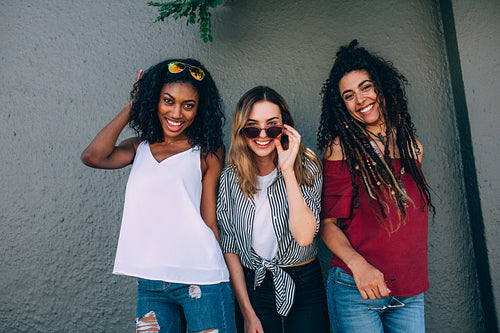 Friends posing for photograph standing against a wall