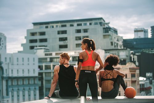 Fitness people relaxing after workout sitting together on rooftop
