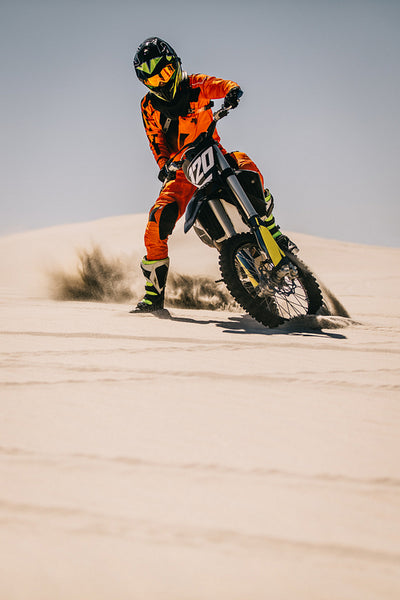 Motocross rider riding over sand dune
