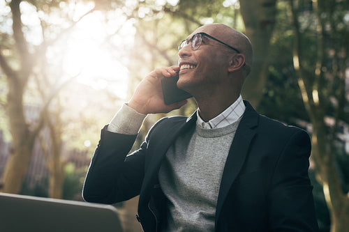 Businessman using laptop and mobile phone sitting outdoors
