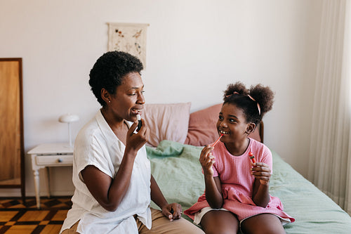 Young girl learning how to apply lipstick from her mom