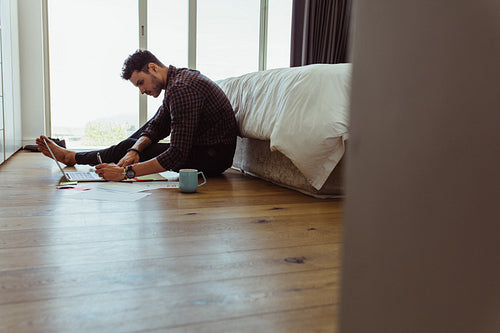Male working on his laptop from his bedroom floor