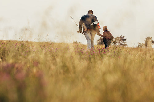 Man walking with kid holding fishing rods