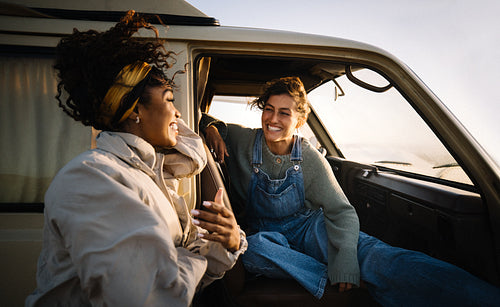 Friends share a joyful moment in a sunny van while chatting and laughing