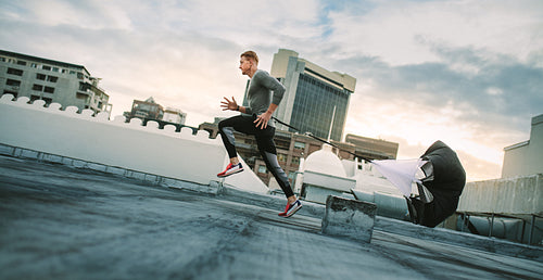 Athlete training on rooftop running with a resistance parachute