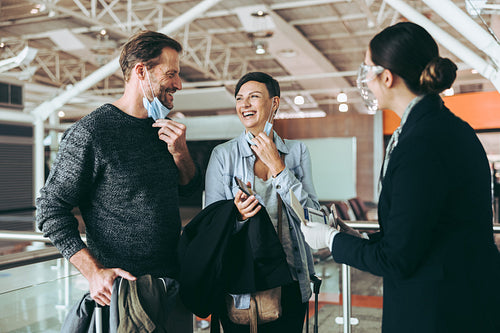 Attendant assisting couple at airport check in counter