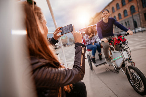 Female taking photographs of friends on tricycle