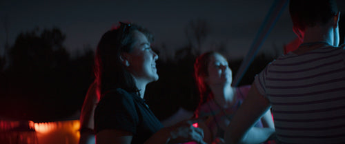 A group of diverse friends dance together at night in front of a festival stage.