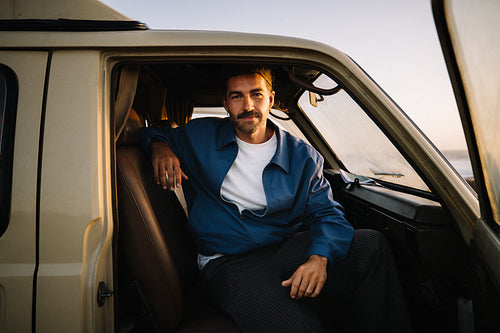 Man sits in a van at sunset feeling confident and relaxed