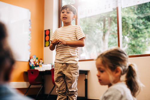 Confident little boy stands in front of his class to give a speech