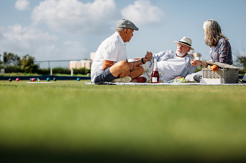 Friends on a day out sitting in a lawn eating food