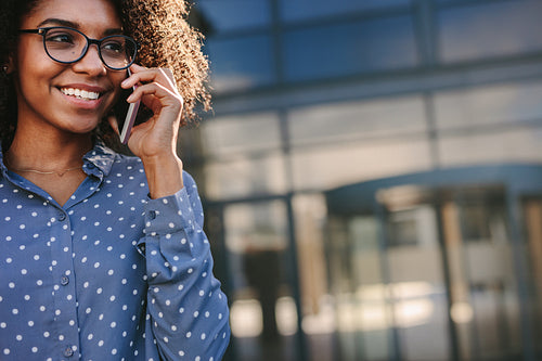 African woman talking over phone and smiling outdoors