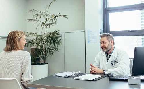 Happy medical doctor talking with woman in clinic