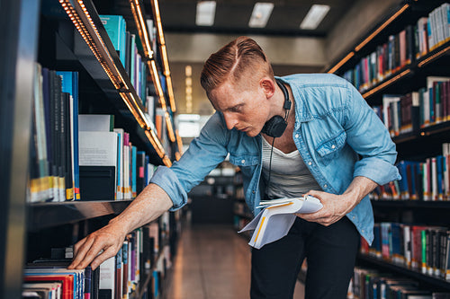 Student looking for a book in shelf
