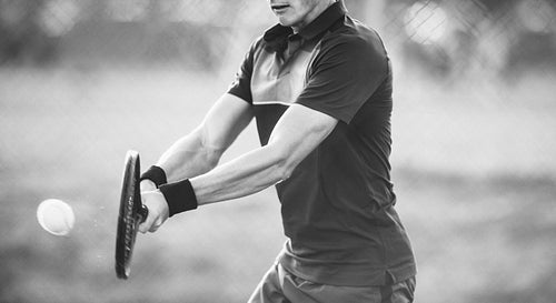 Tennis player hitting backhand in black and white