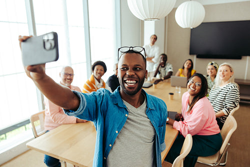 Business colleagues taking a cheerful selfie during a team meeting